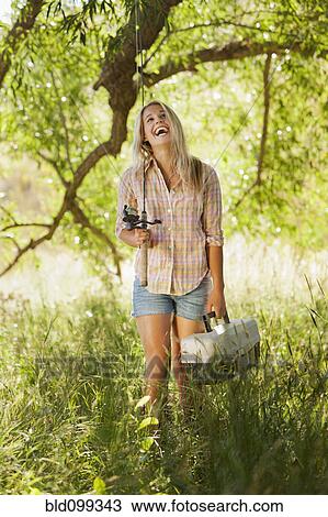Stock Image - Caucasian woman holding fishing pole and tackle box. Fotosearch