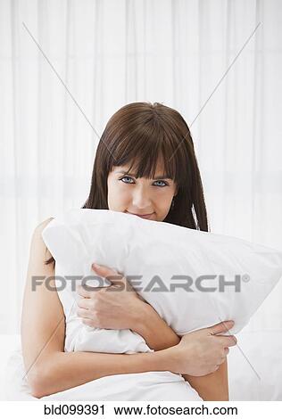 Stock Image - Caucasian woman holding pillow. Fotosearch