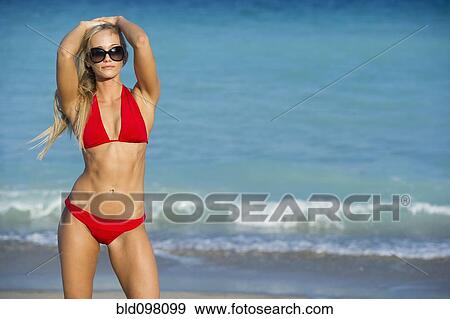 Stock Photo - Caucasian woman in bikini standing on beach. Fotosearch