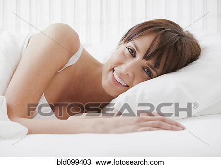 Stock Image - Caucasian woman laying in bed. Fotosearch
