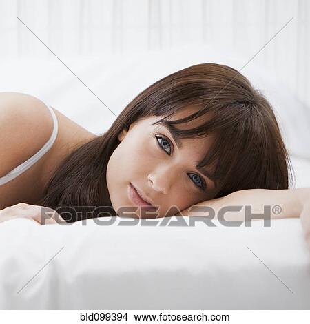 Picture - Caucasian woman laying on bed. Fotosearch