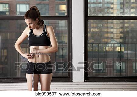 Stock Photo - Caucasian woman measuring her waistline. Fotosearch