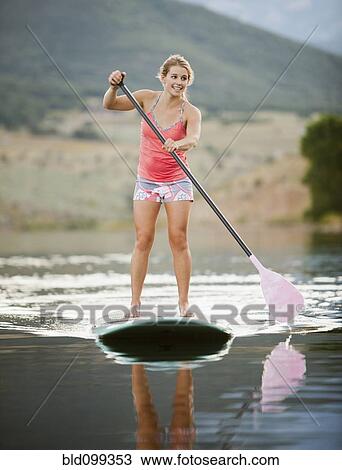 Stock Image - Caucasian woman on stand up paddle board. Fotosearch