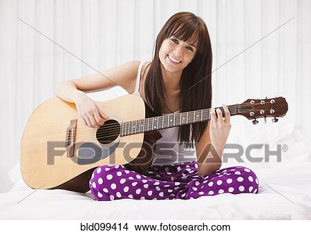 Caucasian woman playing guitar on bed View Large Photo Image Picture - Caucasian woman playing guitar on bed. Fotosearch