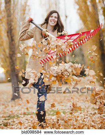 Picture - Caucasian woman raking autumn leaves. Fotosearch