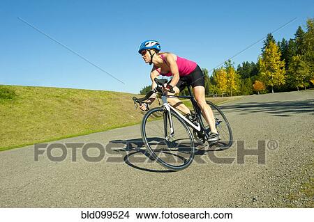 Caucasian woman riding bicycle in park View Large Photo Image Picture - Caucasian woman riding bicycle in park. Fotosearch