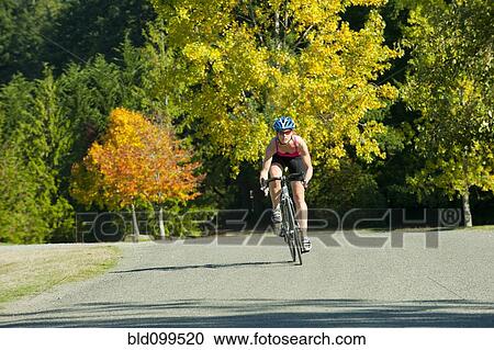 Caucasian woman riding bicycle in park View Large Photo Image Stock Image - Caucasian woman riding bicycle in park. Fotosearch