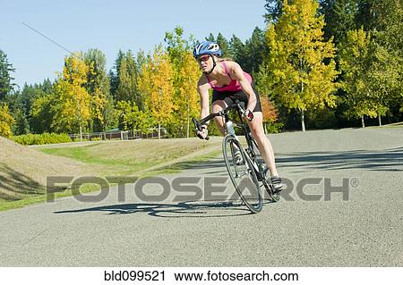 Caucasian woman riding bicycle in park View Large Photo Image Stock Image - Caucasian woman riding bicycle in park. Fotosearch