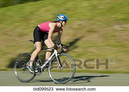 Stock Image - Caucasian woman riding bicycle in park. Fotosearch