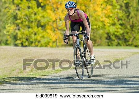 Stock Photo - Caucasian woman riding bicycle in park. Fotosearch