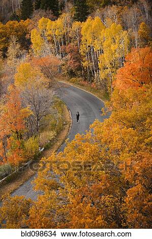 Picture - Caucasian woman running along autumn road. Fotosearch