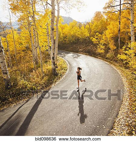 Caucasian woman running along autumn road View Large Photo Image Stock Photograph - Caucasian woman running along autumn road. Fotosearch