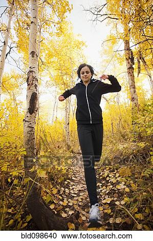 Stock Image - Caucasian woman running in autumn forest. Fotosearch
