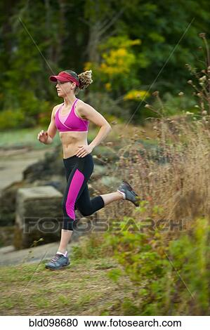 Stock Image - Caucasian woman running in park. Fotosearch