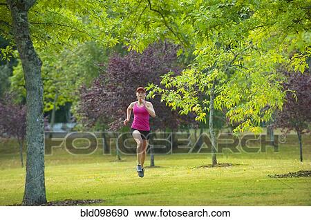 Stock Image - Caucasian woman running in park. Fotosearch