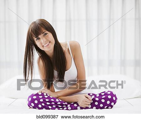 Stock Photo - Caucasian woman sitting on bed. Fotosearch