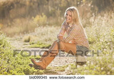 Stock Photography - Caucasian woman sitting on tackle box in field. Fotosearch