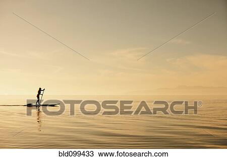 Caucasian woman standing on paddle board View Large Photo Image Stock Image - Caucasian woman standing on paddle board. Fotosearch