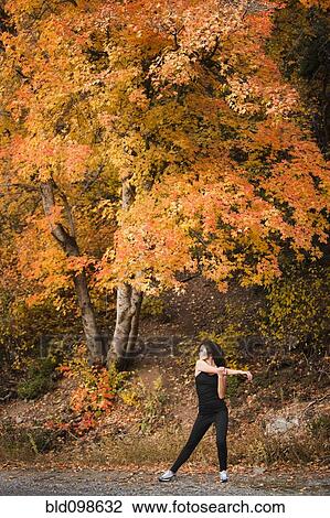Stock Image - Caucasian woman stretching in autumn road. Fotosearch