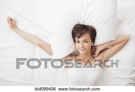 Stock Photograph - Caucasian woman stretching in bed. Fotosearch