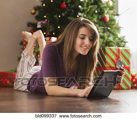 Stock Photo - Caucasian woman using digital tablet at Christmas time. Fotosearch