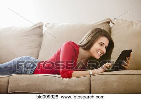 Stock Photography - Caucasian woman using digital tablet on sofa. Fotosearch