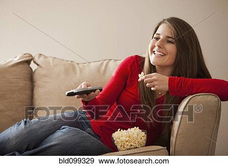 Caucasian woman watching television and eating popcorn View Large Photo Image Stock Photo - Caucasian woman watching television and eating popcorn. Fotosearch