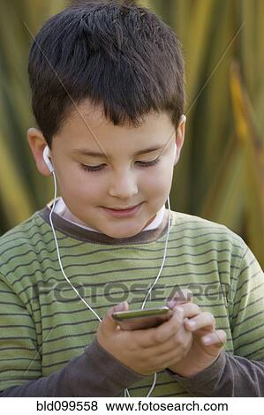 Stock Photo - Chilean boy listening to music on mp3 player. Fotosearch