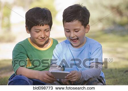 Stock Image - Chilean boys looking at cell phone. Fotosearch