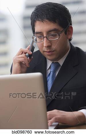 Stock Image - Chilean businessman using cell phone and laptop. Fotosearch