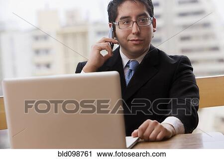 Stock Image - Chilean businessman using cell phone and laptop. Fotosearch