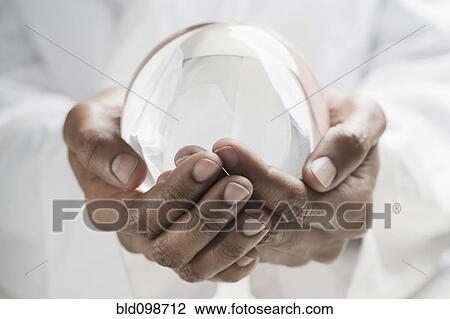Stock Image - Close up of mixed race man holding crystal ball. Fotosearch