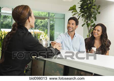 Stock Image - Couple checking in to hotel. Fotosearch