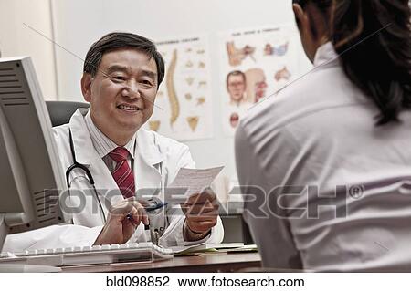Stock Image - Doctor talking to patient in office about prescription. Fotosearch
