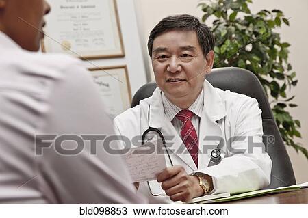 Stock Image - Doctor talking to patient in office about prescription. Fotosearch