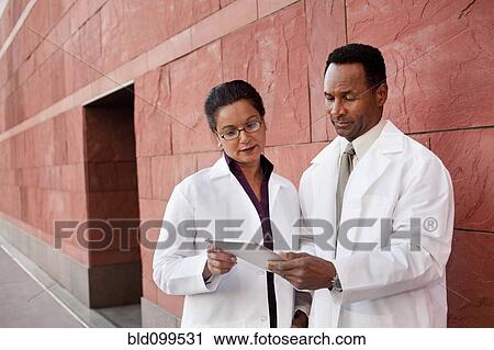 Stock Image - Doctors using digital tablet outdoors. Fotosearch