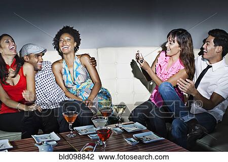 Stock Image - Friends drinking cocktails in nightclub. Fotosearch
