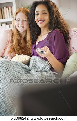 Friends eating popcorn and watching television View Large Photo Image Stock Image - Friends eating popcorn and watching television. Fotosearch