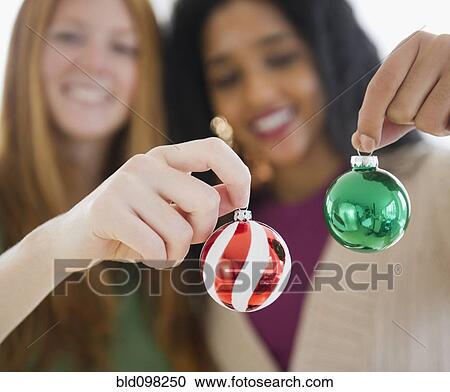 Stock Image - Friends holding small Christmas ornaments. Fotosearch