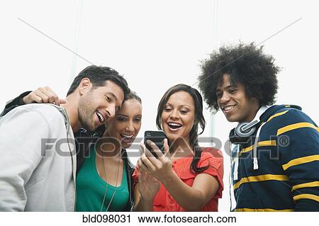 Stock Image - Friends looking at cell phone. Fotosearch