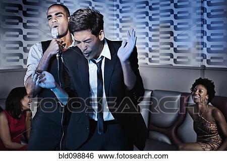 Stock Photograph - Friends singing karaoke in nightclub. Fotosearch