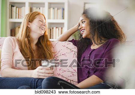 Stock Image - Friends sitting on sofa talking. Fotosearch