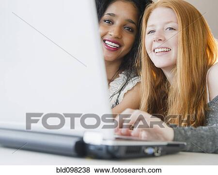 Stock Photo - Friends using laptop together. Fotosearch