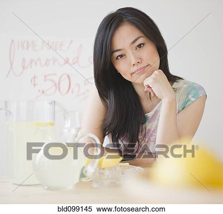 Stock Photography - Frustrated Japanese woman sitting at lemonade stand. Fotosearch