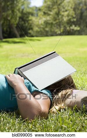 Girl sleeping in grass with book on her head View Large Photo Image Stock Photography - Girl sleeping in grass with book on her head. Fotosearch
