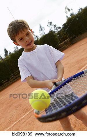 Stock Photo - Hispanic boy balancing tennis ball on racquet. Fotosearch