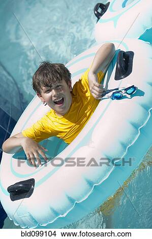 Hispanic boy floating on raft in swimming pool View Large Photo Image Picture - Hispanic boy floating on raft in swimming pool. Fotosearch