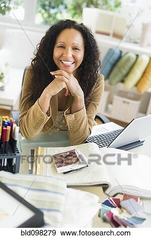 Stock Photo - Hispanic businesswoman sitting at desk with laptop. Fotosearch
