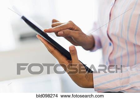 Picture - Hispanic businesswoman using digital tablet in office. Fotosearch