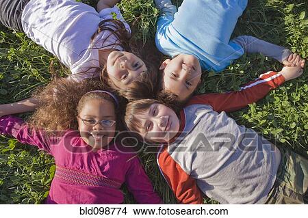 Picture - Hispanic children laying in grass together. Fotosearch